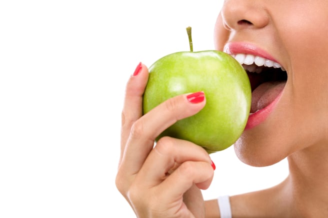 woman biting a green apple isolated on white